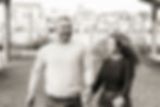 Black and white photo of husband and wife running in the garden of the Lewes boat yard. The moms hair is blowing in the wind and the dad has his largest smile EVER. The couple is looking towards each other while having a real moment of fun together.