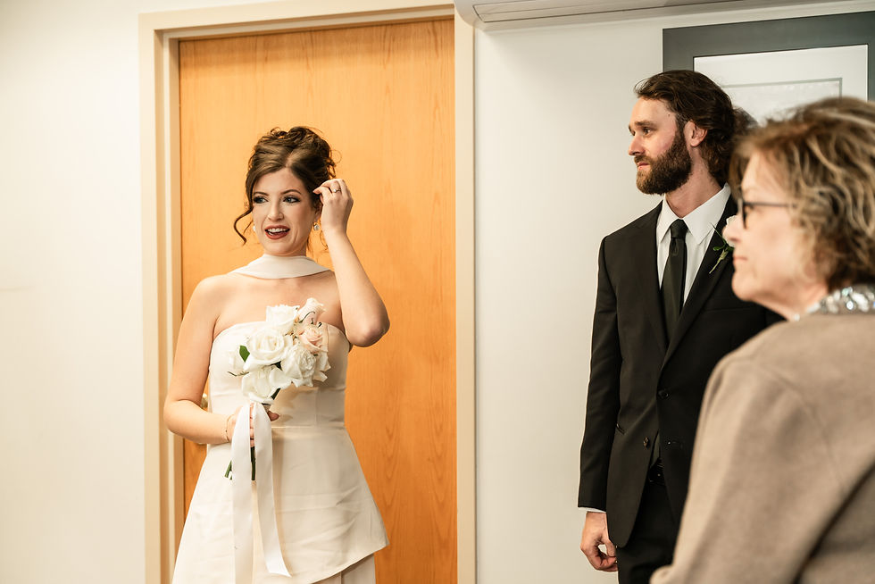 bride inside the Sussex courthouse in Georgetown, Delaware where she is framed in the doorway while fixing her hair.