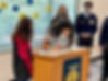 Student signs document for NC FFA membership, surrounded by peers