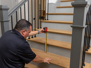 Home inspector checking step riser height during an evaluation focused on proper stairways and safety glass requirements.