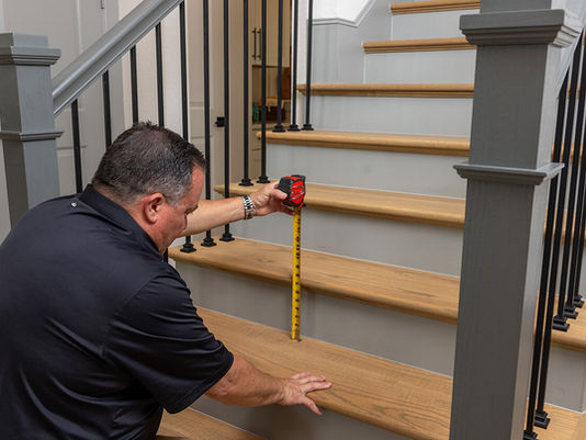 Home inspector checking step riser height during an evaluation focused on proper stairways and safety glass requirements.