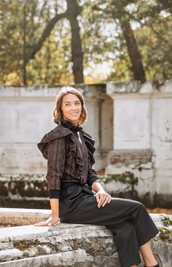 Femme assise sur un muret souriante