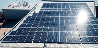 Large industrial rooftop covered with high-efficiency solar panels. Dramatic sunlight, sha