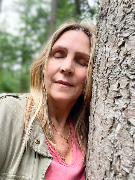 Pavanne Veltman with her eyes closed, resting her face against a tree