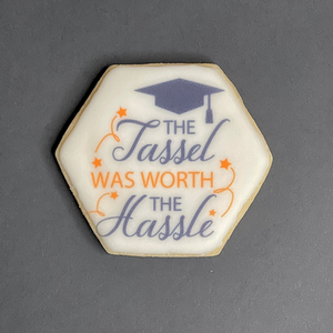 Decorated hexagonal graduation cookie with the quote "The tassel was worth the hassle" in calligraphy.