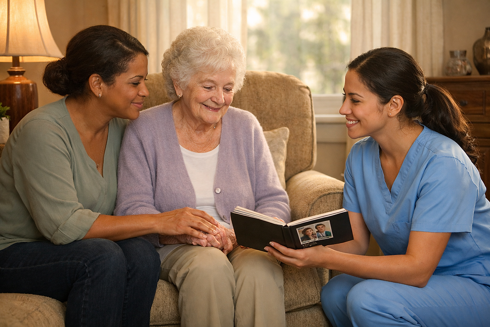Two caregivers smile with an elderly woman on a couch, looking at a black photo album in a warm living room.