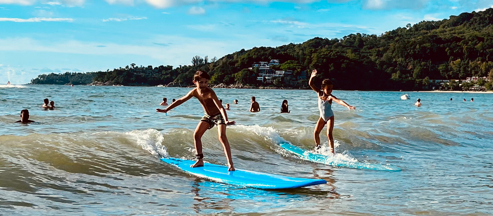 Enfant debout sur une planche de surf en mousse à Kamala, Phuket