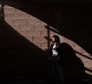 Woman standing in sunlight, brick wall background