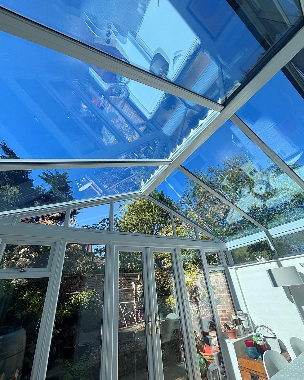 Bright conservatory with a clear view of the blue sky through the newly-cleaned glass roof.