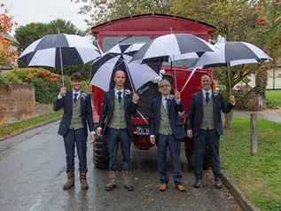 Grooms party with umbrellas and vintage fire engine brave the rain