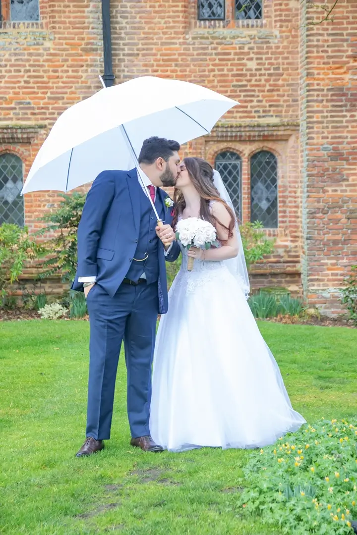 Bride and groom with white umbrella in the grounds of Leez Priory