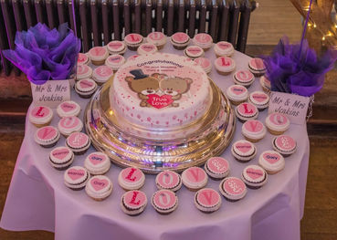 Single layer wedding cake surrounded by cupcakes