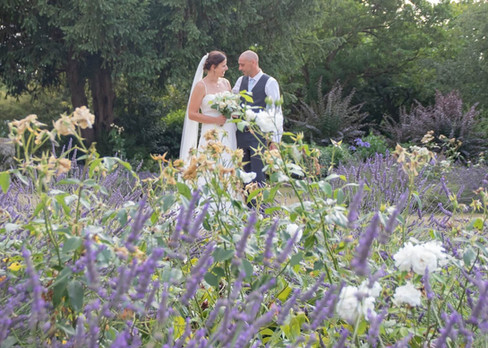 Bride and groom surrounded by summer flowers in the gardens at Langtons House