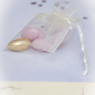 White voile bag with ribbon containing gold,pink and white sugared almonds