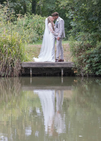 Bride and groom refkected in the lake at Newland Hall