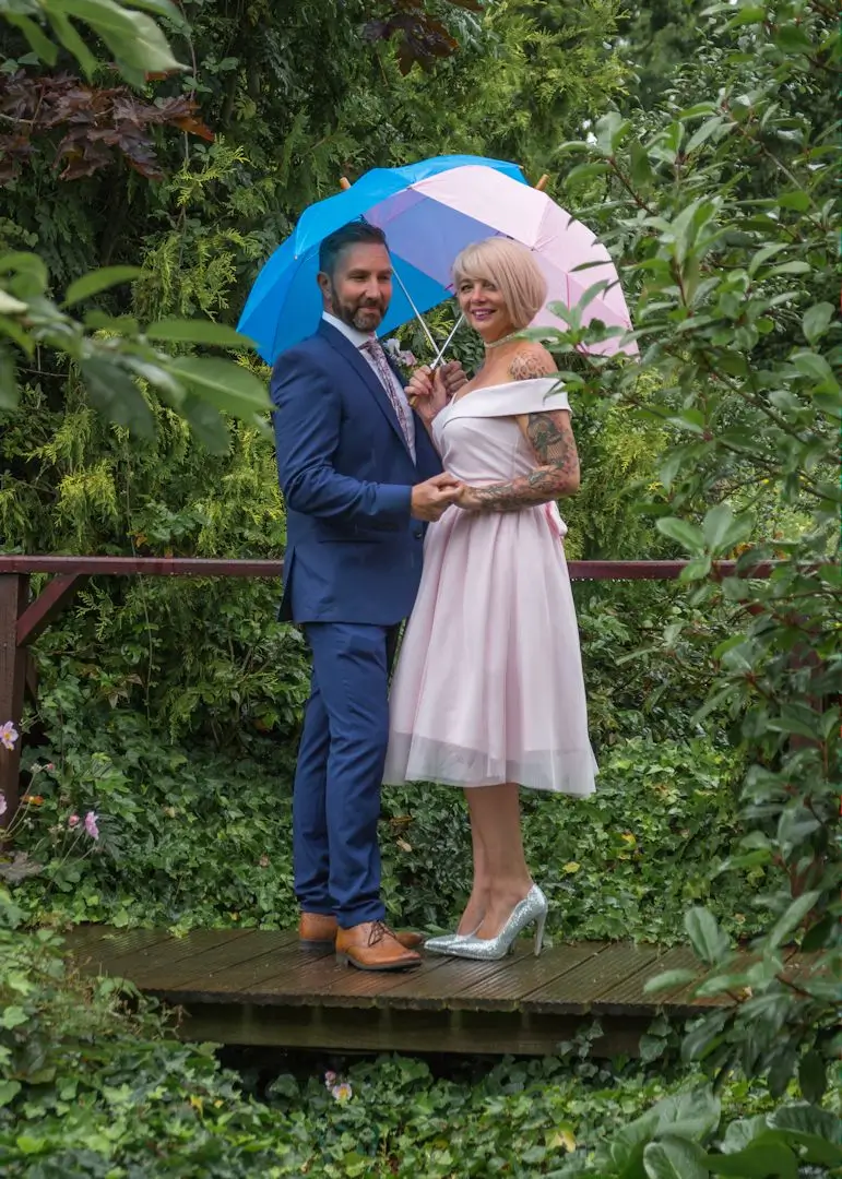 Bride and groom brace the rain with umbrellas to match their outfits at Ivy Hill Hotel, Margaretting