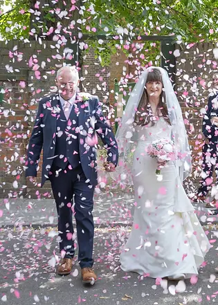 Bride and groom surrounded by a shower of pink and white confetti at Langtons House, Hornchurch