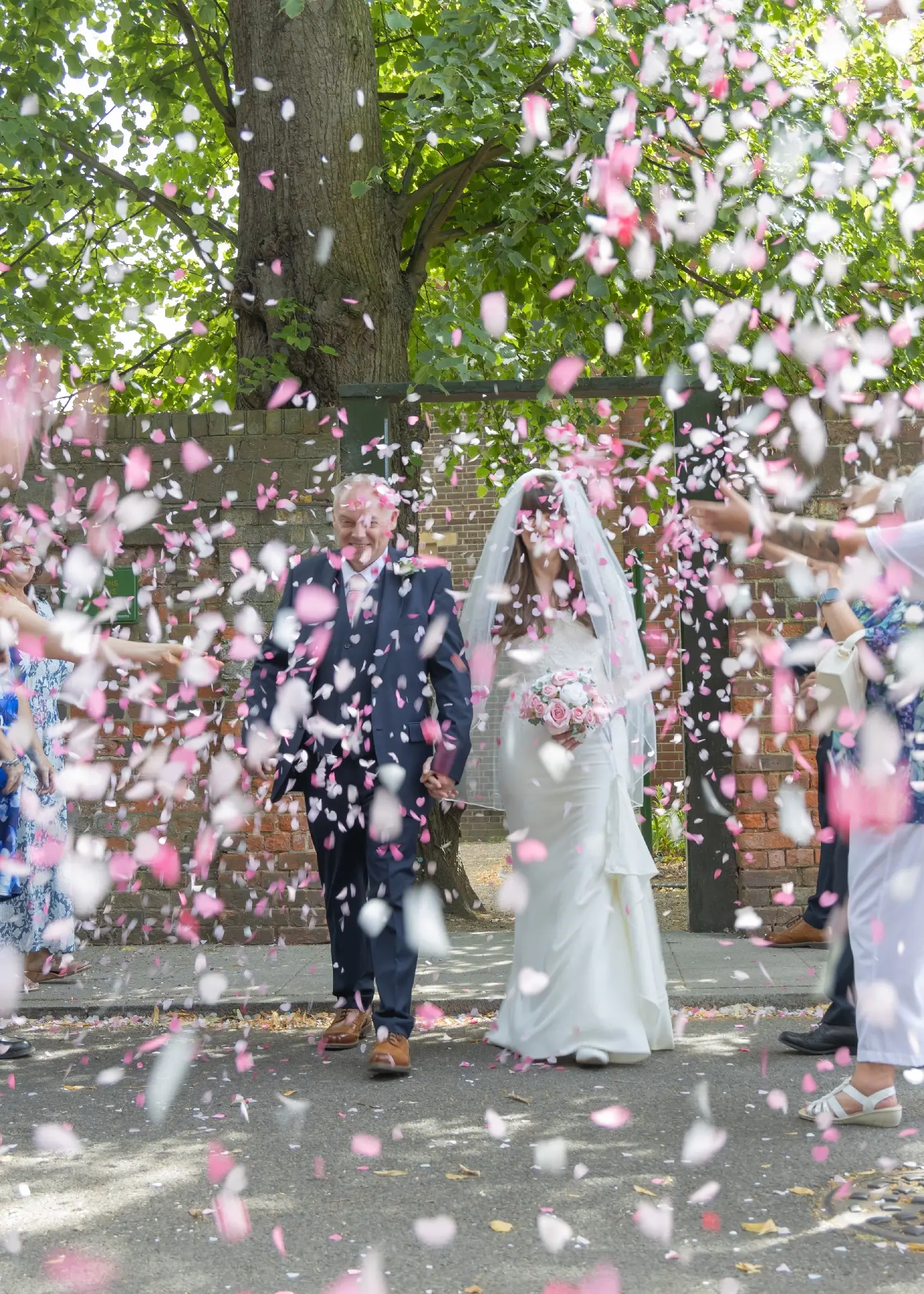 Bride and groom are surrounded by confetti in the sunshine at Langtons House