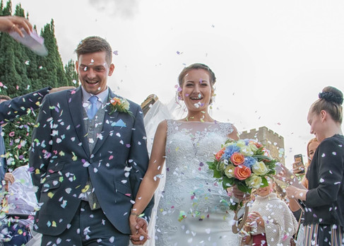 Bride and groom laugh as they showered with wedding confetti
