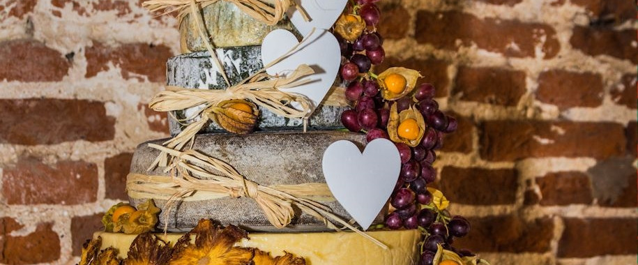 Cheese Wedding Cake with wooden hearts and rustic fruit decoration on a wooden plinth