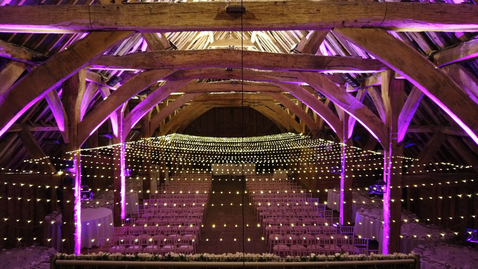 Fairy lights strung across the wedding ceremony are with purple accent lights