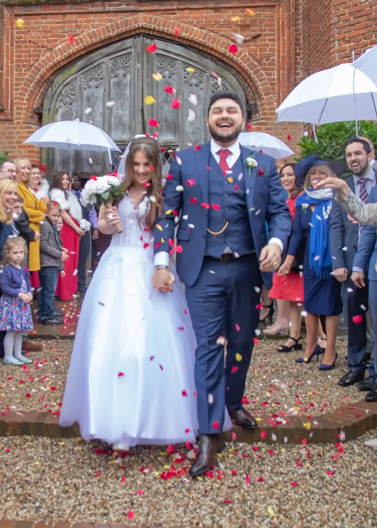 Bride and groom showered in confetti on a rainy day at Leez Priory