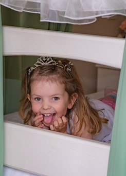 Flower girl sticks out her tongue and smiles during bridal preparations