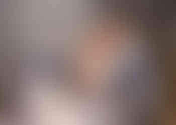 Bride and groom kiss as they cut their wedding cake in the garden room at Wivenhoe House Hotel