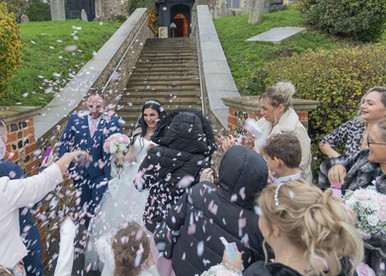 Bride and groom are showered with confetti at the bottom of the steps at St Nicholas church in Laindon