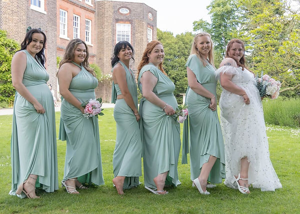 Bride and bridesmaids in sage green show off their shoes in the grounds at Langtons House