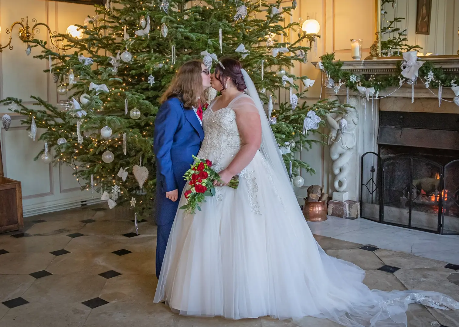 Bride and groom kissing by a Christmas tree at Gosfield Hall