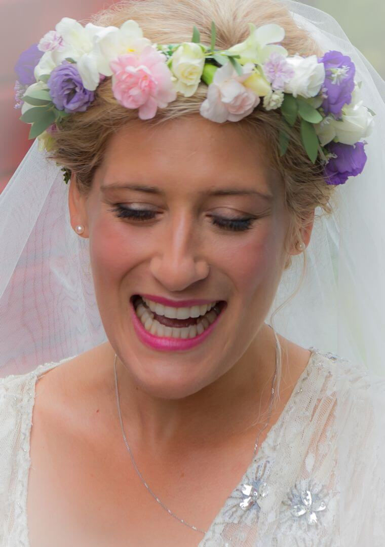 Bride gazes down showing off her pastel flower crown ready for her summer wedding at Great Lodge in Bardfield