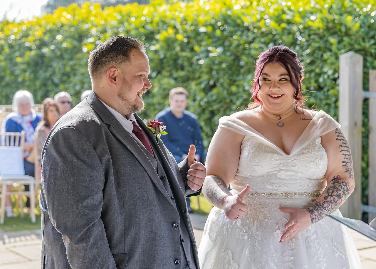 Bride and groom give each other the thumbs up at the start of their outdoor ceremony at Forrester Park Golf Club