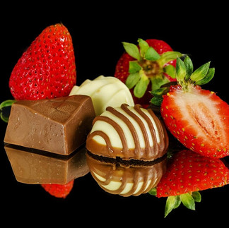 Strawberries and chocolates on a reflective surface