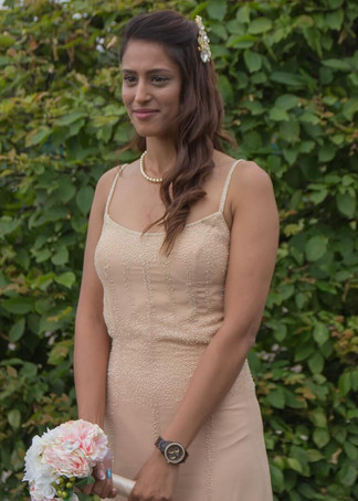 Bride in peach dress with pale flower posy and string of pearls