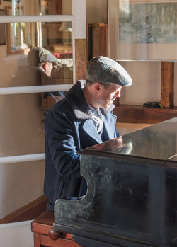 Groom relaxes whilst playing the piano at The Reid Rooms before getting ready