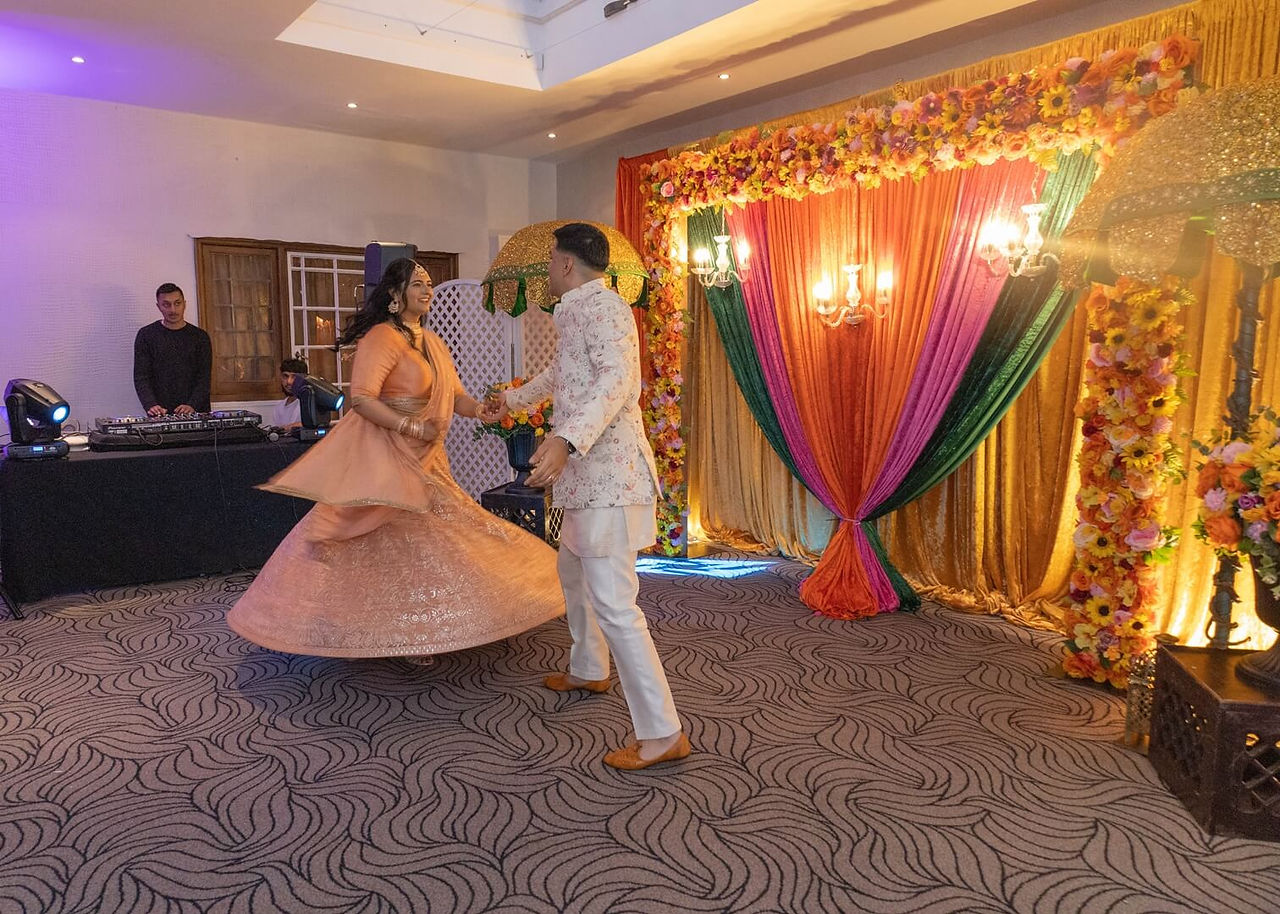 Bride and groom in traditional indian dress dancing at Prested Hall