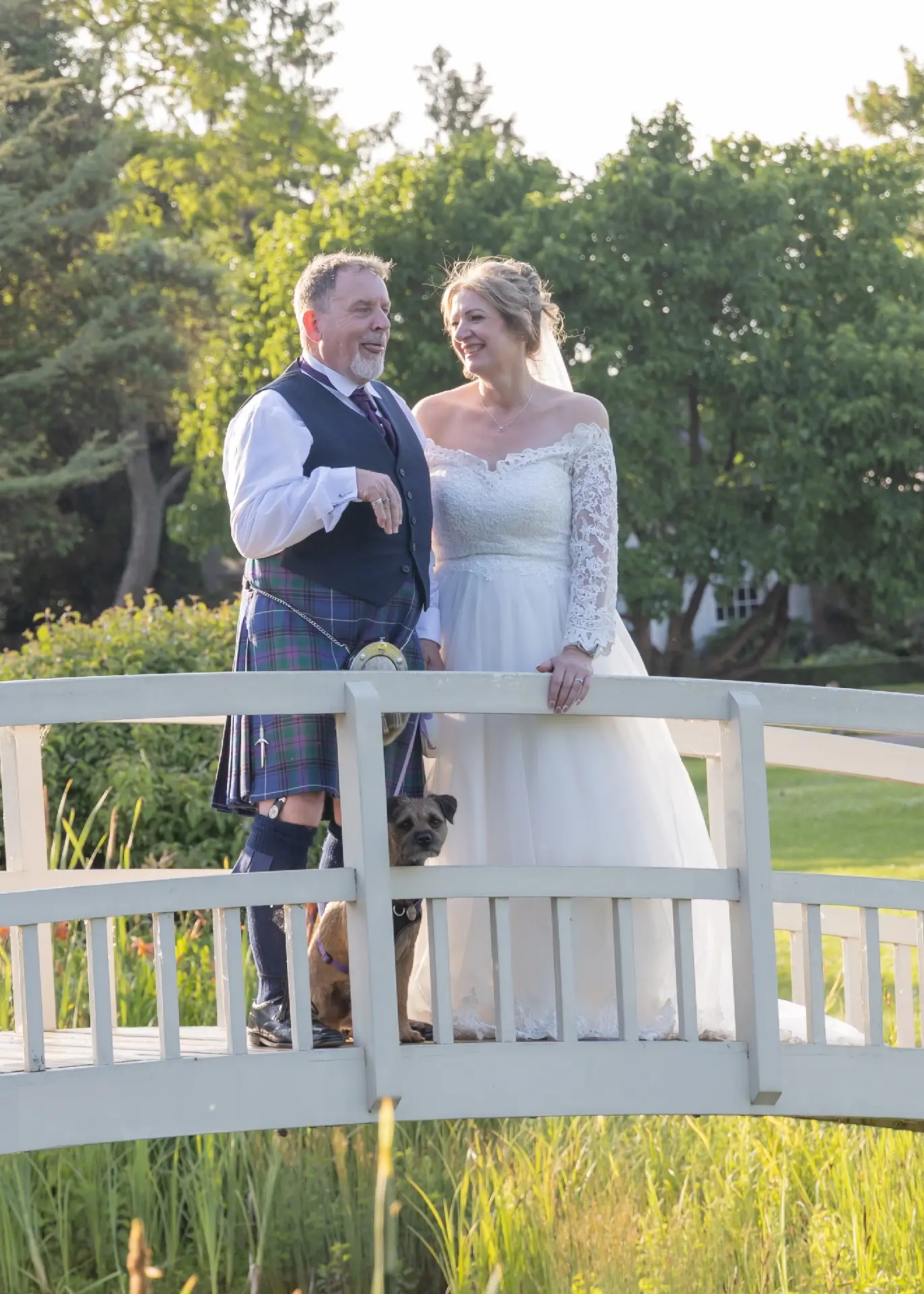 Bride and groom on the bridge with their dog at The Fennes