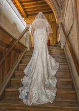 Rear view of brides full length lacy train on the stairs at Hedingham castle