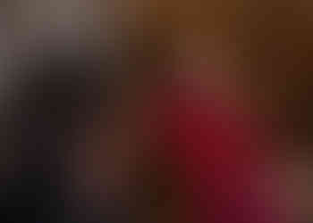 Medieval bride giggles whilst wearing a crown and red velvet cloak