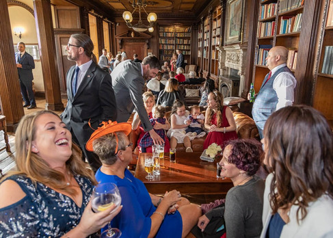 Guests in the library at Gosfield Hall socialising before the wedding ceremony