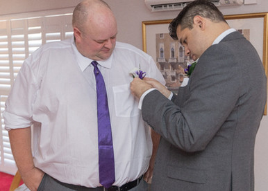 Best man pins on the grooms buttonhole during preps at Ye Olde Plough House in Essex