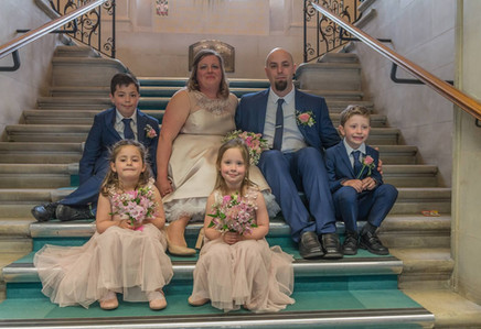 Bride and groom with children sitting on the steps at Braintree Town Hall in Essex