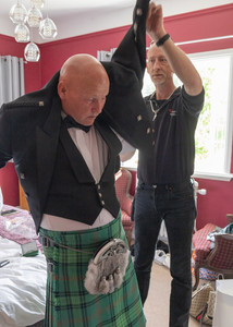 Essex wedding photographer helps the groom with his black waistcoat at Prested Hall