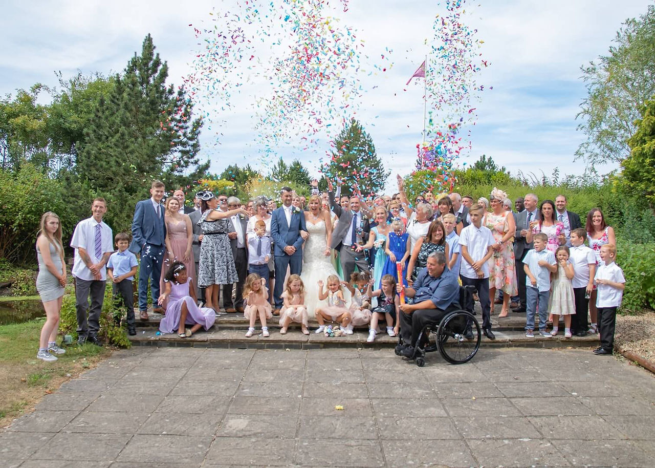 Wedding group photo taken as confetti cannons are fired at Five Lakes, Colchester in Essex