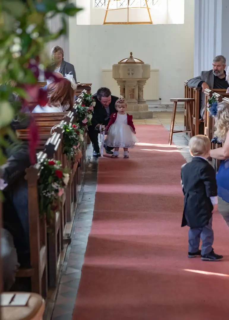 Young wedding guests before the ceremony begins at St Mary The Virgin church at Layer Marney