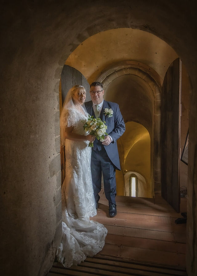 Bride and groom inside Hedingham Castle with soft golden lighting