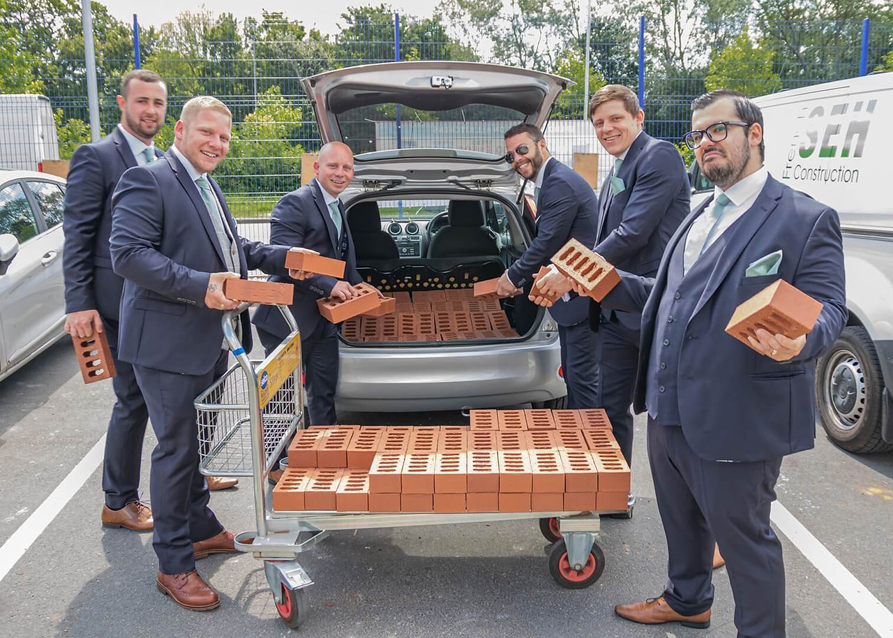 Grooms party help load a customers bricks after their builders breakfast in Basildon