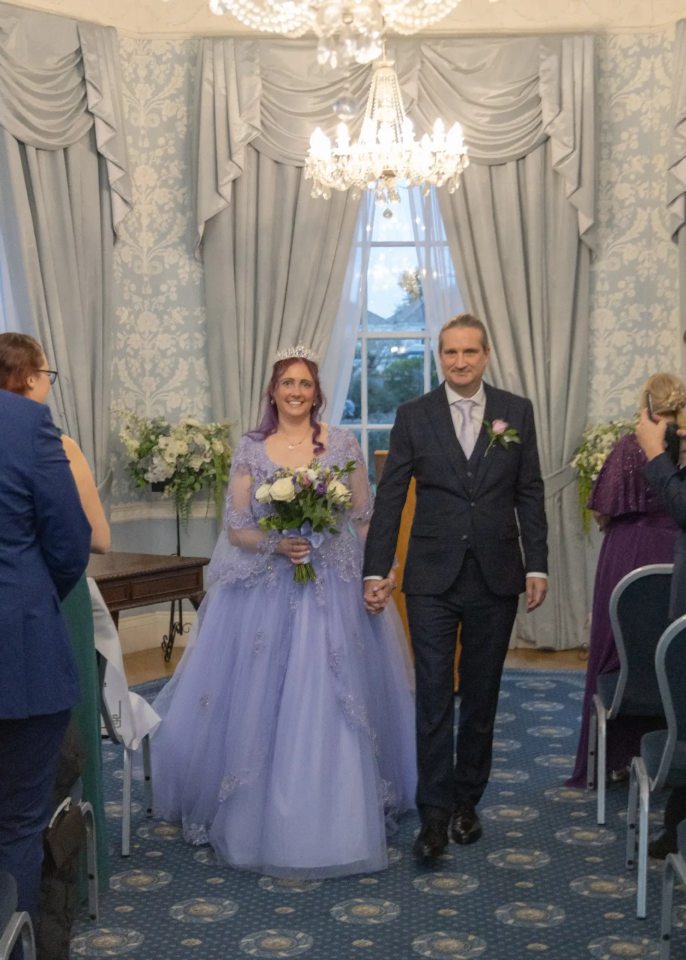 Bride in lilac with her groom leave the wedding ceremony at Langtons House