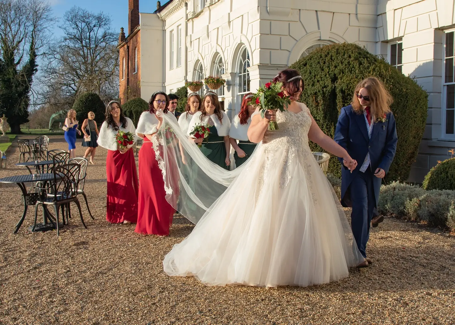 Wedding party walking along the terrace in the winter sunshine at Gosfield Hall